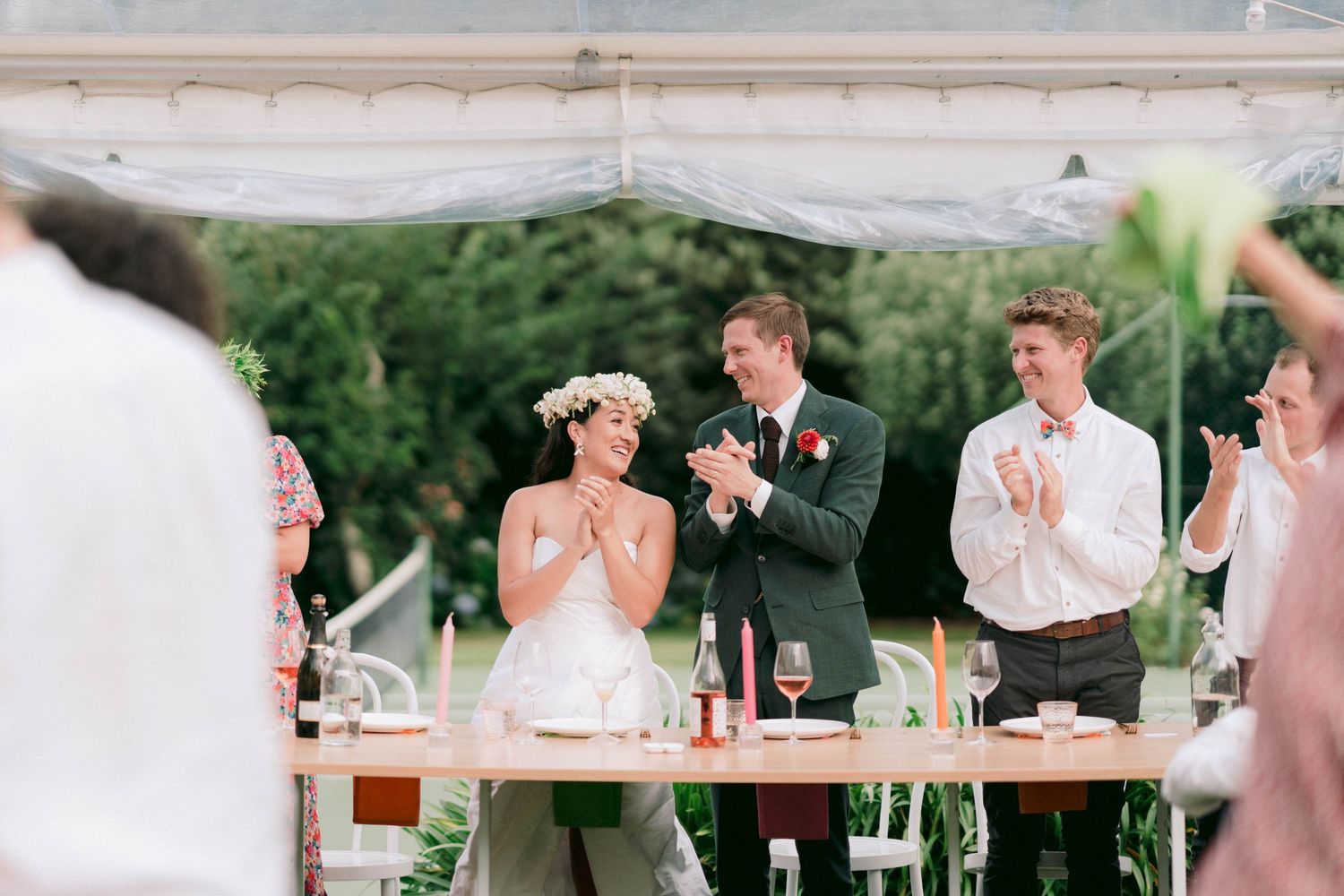 A celebratory moment during wedding speeches under a white tent.