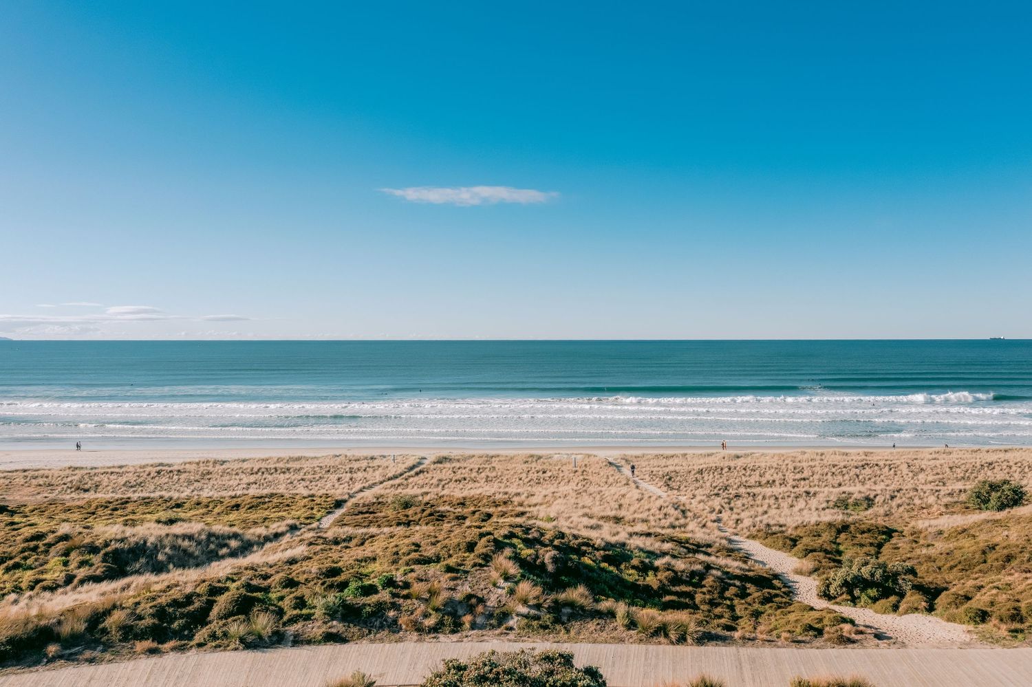 Panoramic view of pristine beach coastline with turquoise waters and clear blue sky.