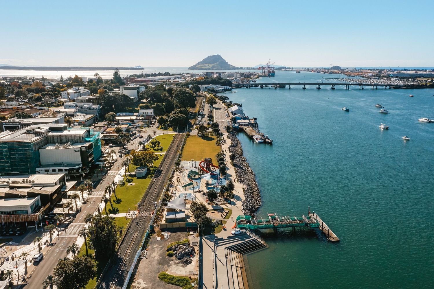 Aerial panorama of industrial docks and waterways along a coastal harbor with shipping terminals and moored vessels.