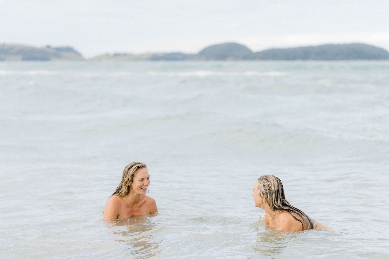 Two people relaxing in calm ocean waters at dusk.