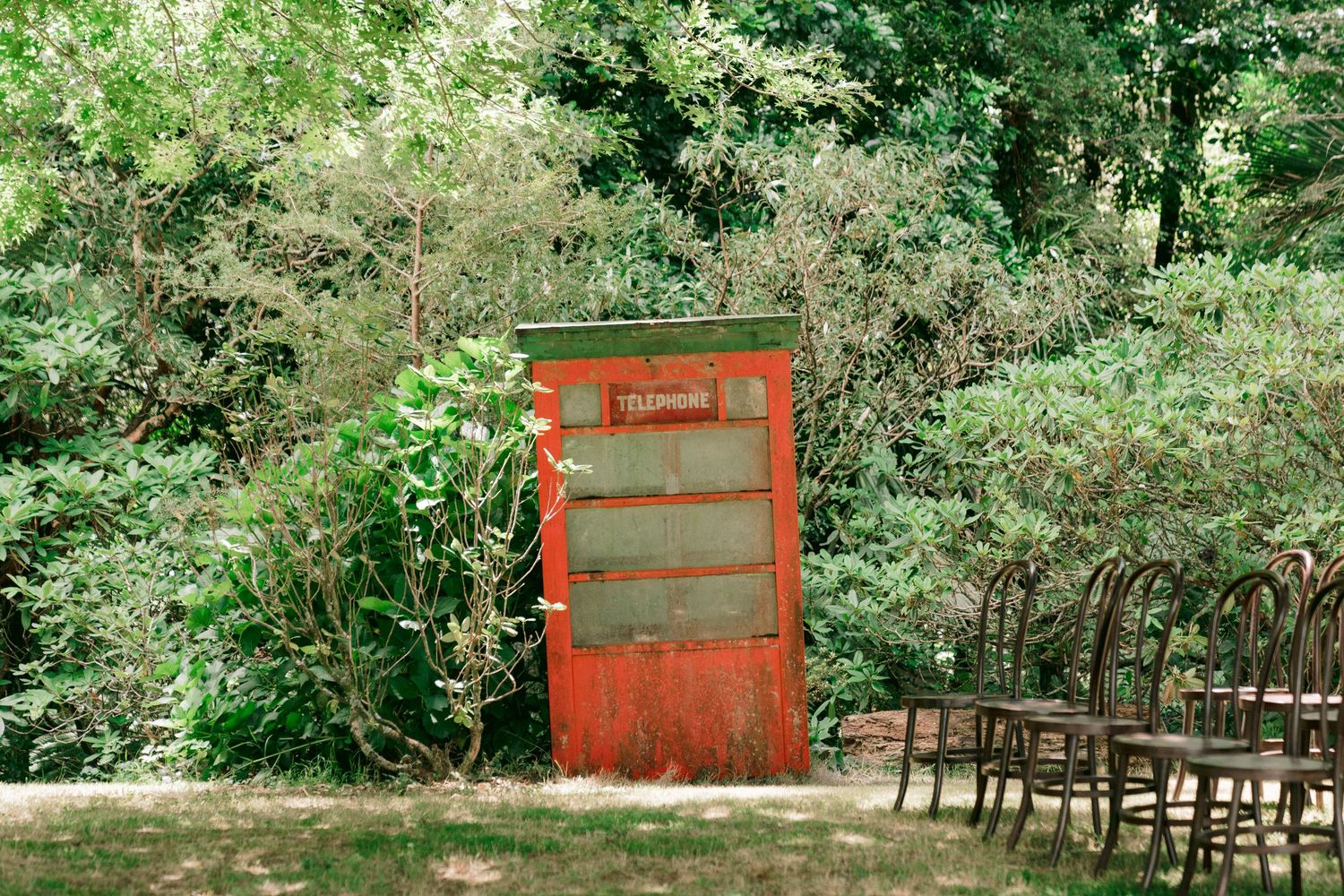 Outdoor wedding venue setup with red accents among lush green foliage.