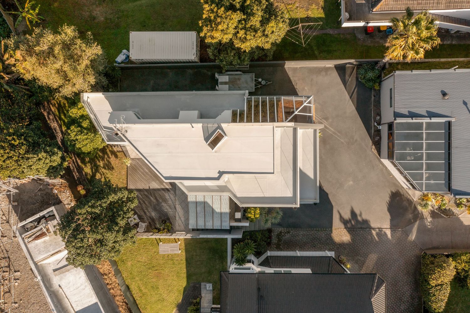 Bird's eye view of modern white house with rooftop deck and neat landscaping.