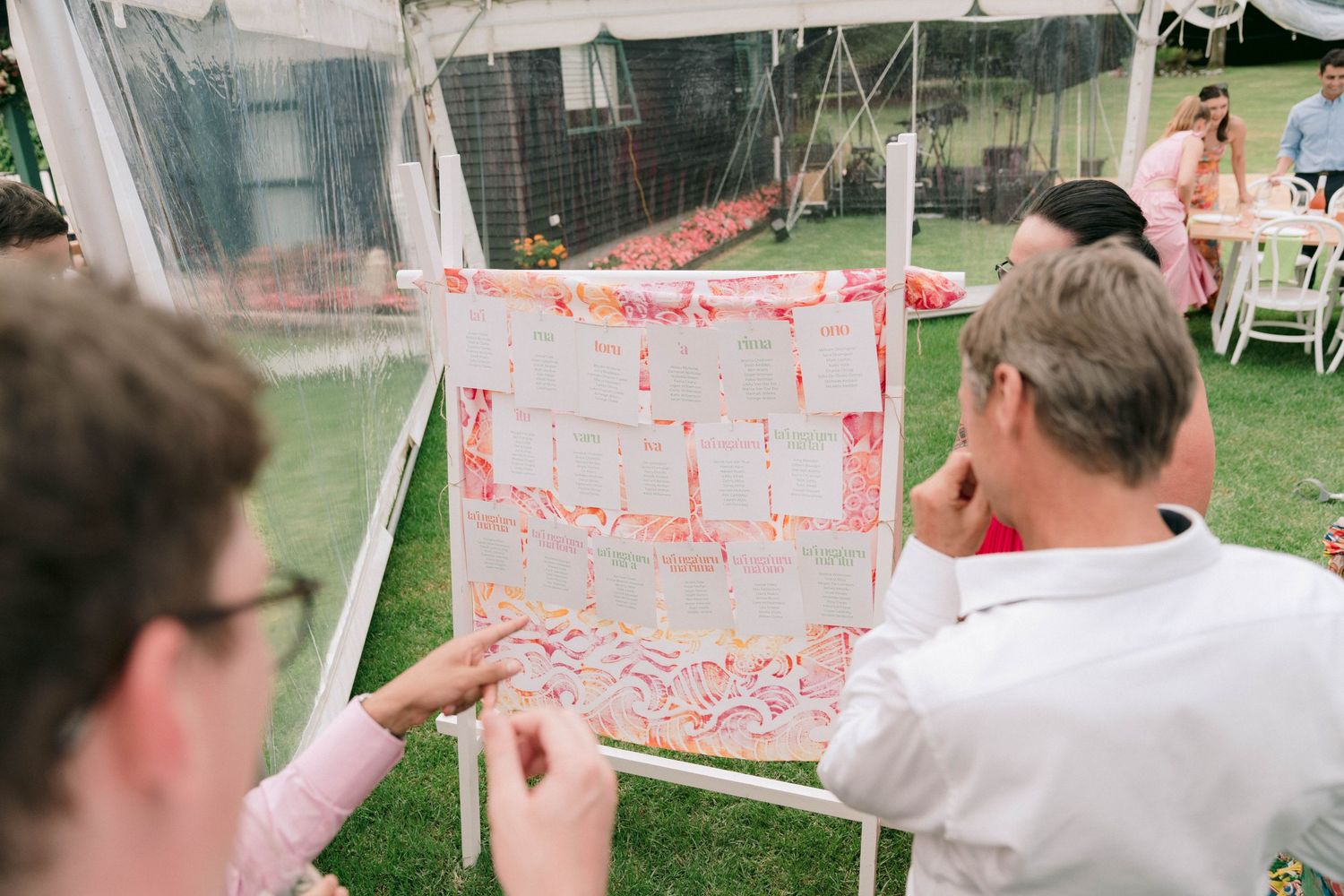 People examining a map or diagram displayed on a clear surface at an outdoor event.