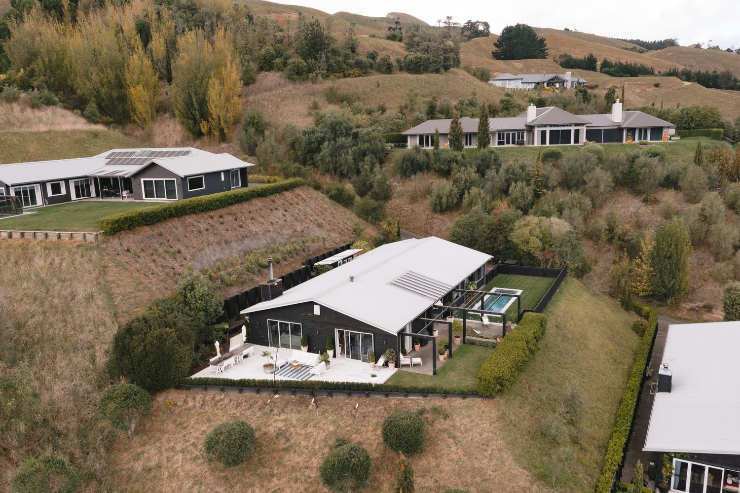 Modern luxury home with white exterior nestled in rolling hills with panoramic landscape views.