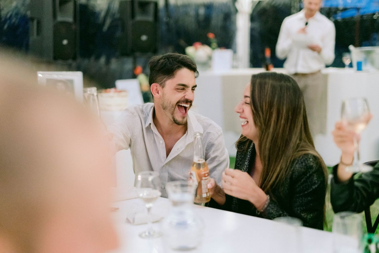 Wedding guests socializing and laughing together at reception tables.