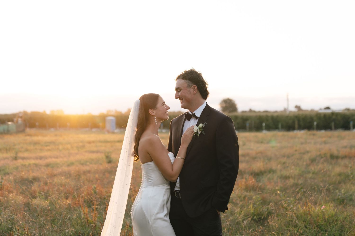 Romantic sunset portrait of newlyweds in golden field.