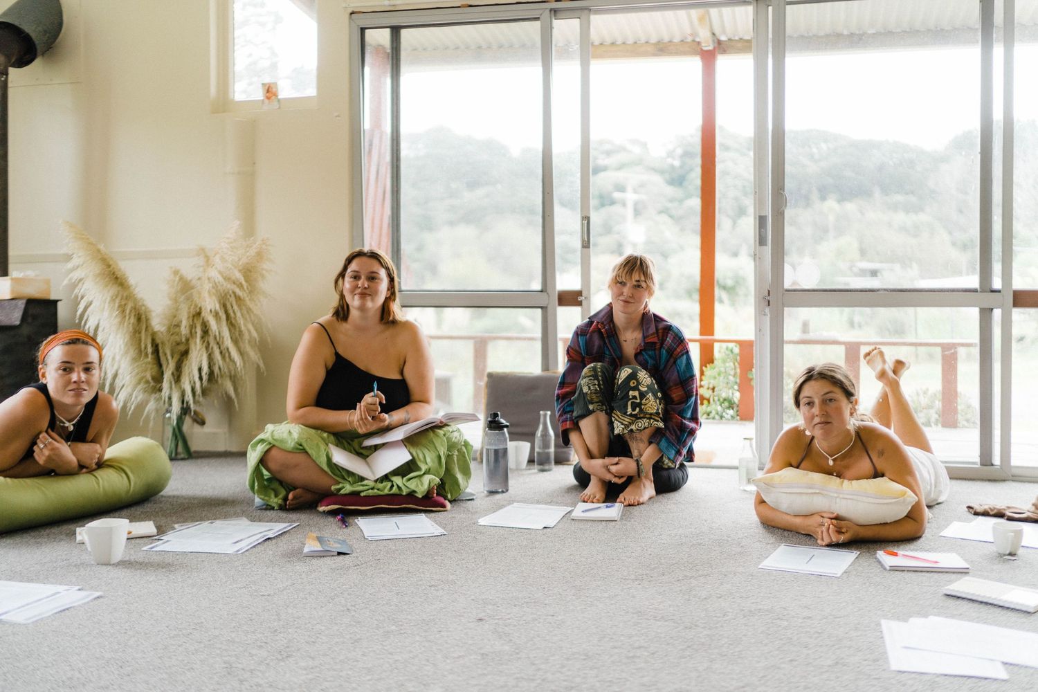 People sitting in a circle on yoga mats during a wellness retreat in a bright room.