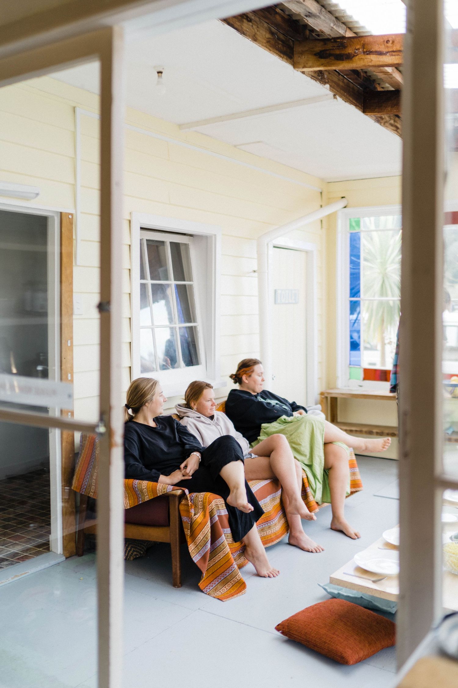 Cozy porch scene with people lounging on orange striped cushions.