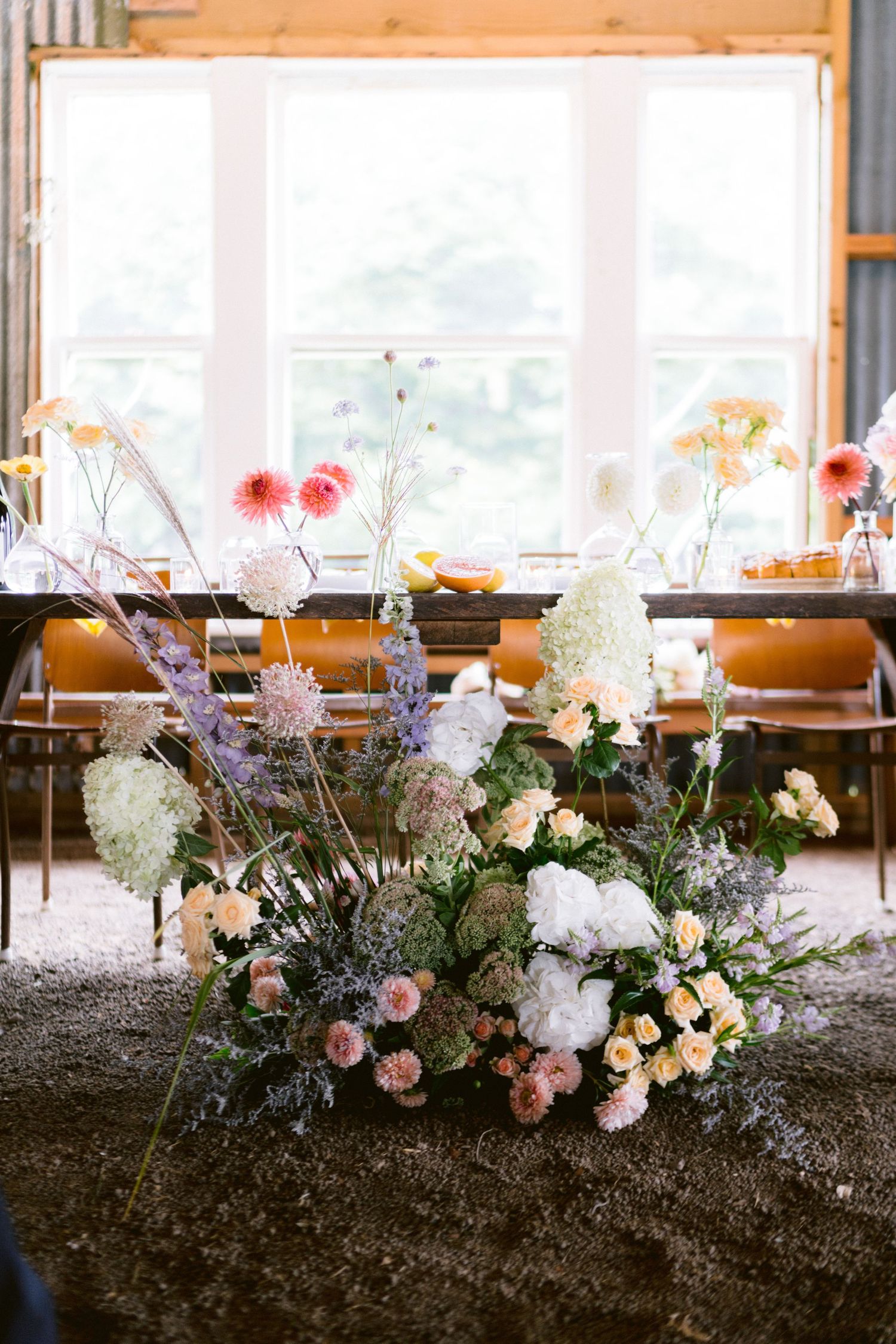 Elegant floral centerpiece with wildflowers and hydrangeas against a bright window.