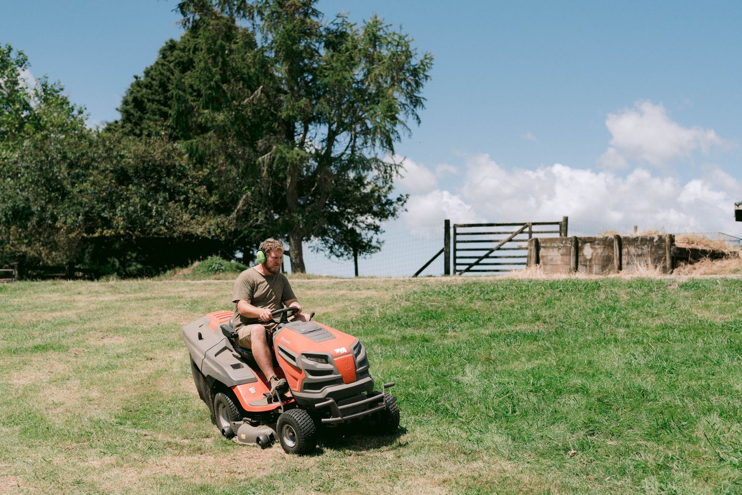 A black utility vehicle with trailer parked in a grassy field on a sunny day.