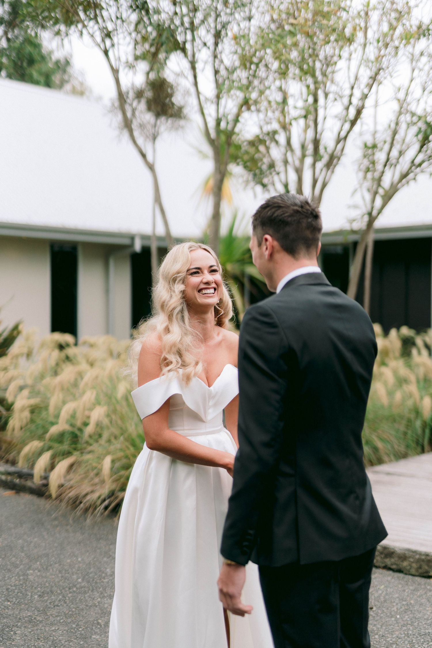 First look wedding moment captured in an outdoor garden setting with pampas grass.