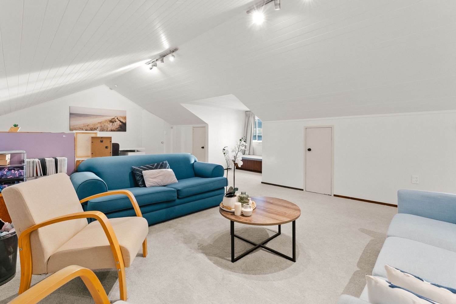 Modern attic living area with blue sofa and contemporary wooden furniture.