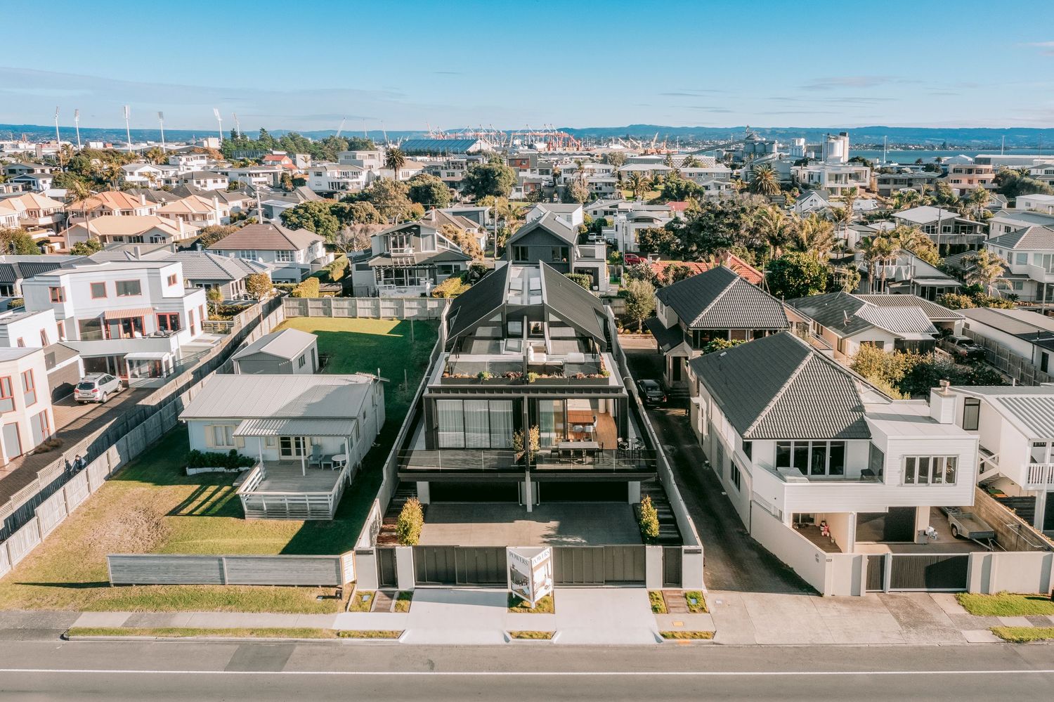 Bird's eye view of luxury modern homes along a suburban street with clean architectural lines.