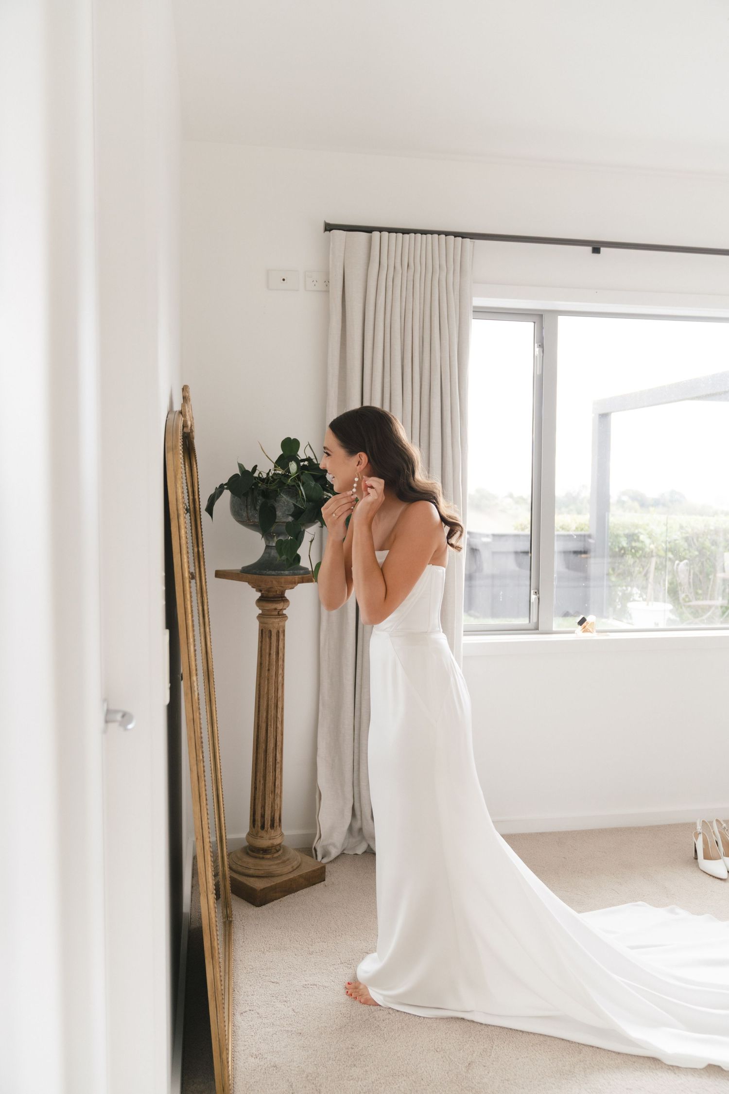 Bridal preparation scene in an all-white modern room with long flowing wedding dress.