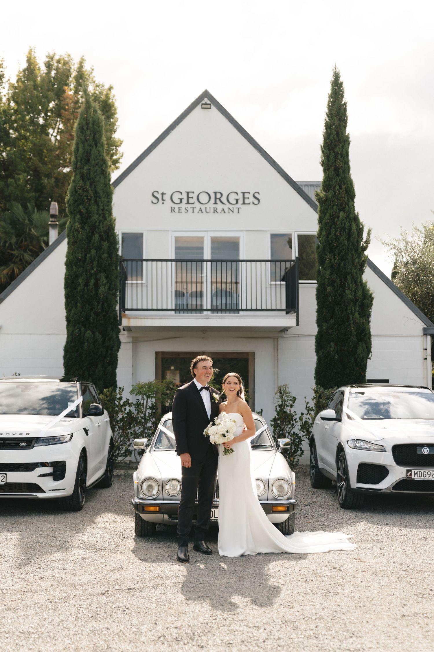 Elegant white building with St Georges Restaurant signage and cypress trees framing the entrance.