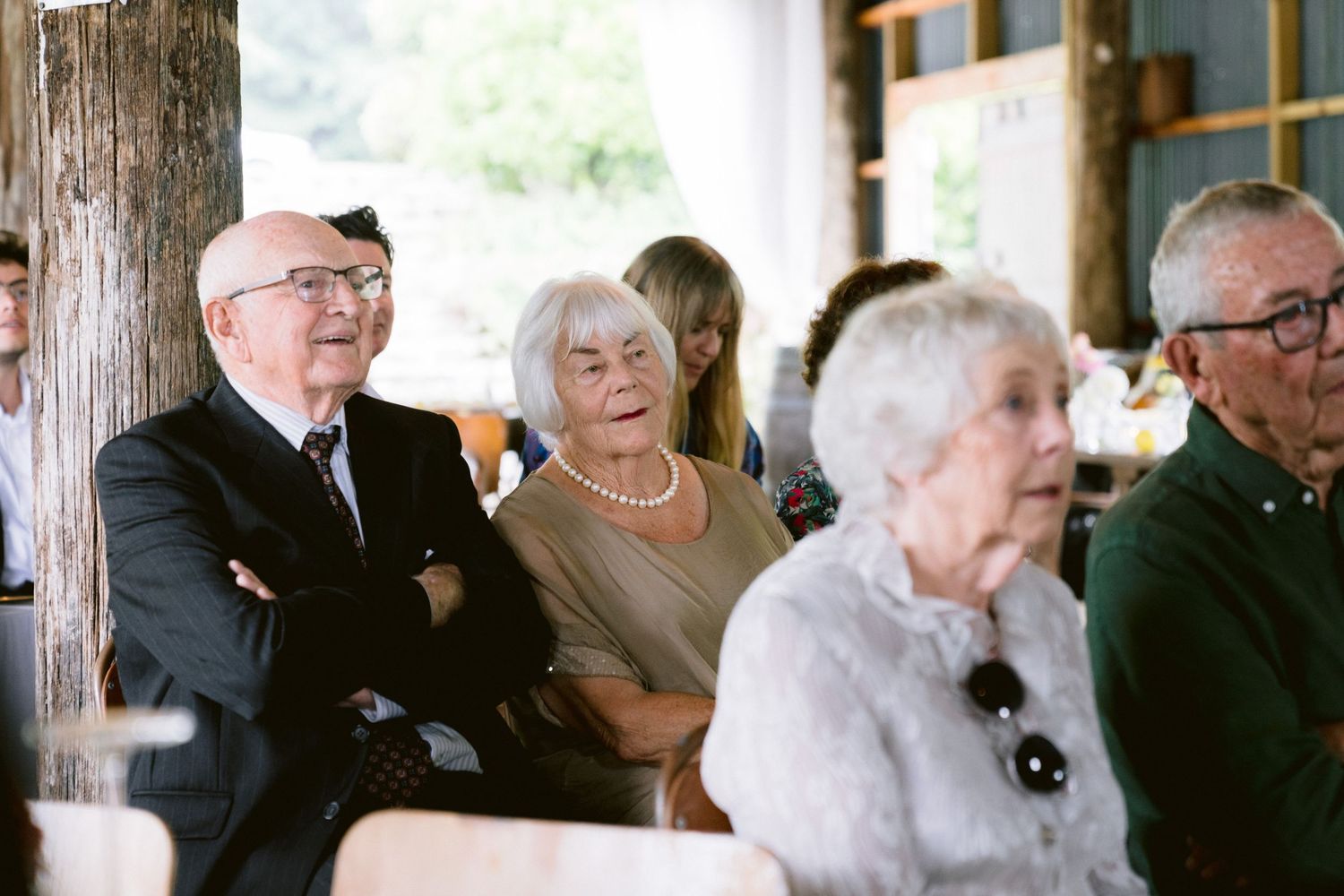 Wedding guests seated in formal attire at an indoor ceremony venue.