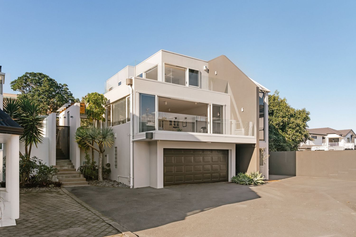 Modern white residential building exterior with multiple units and clean architectural lines.