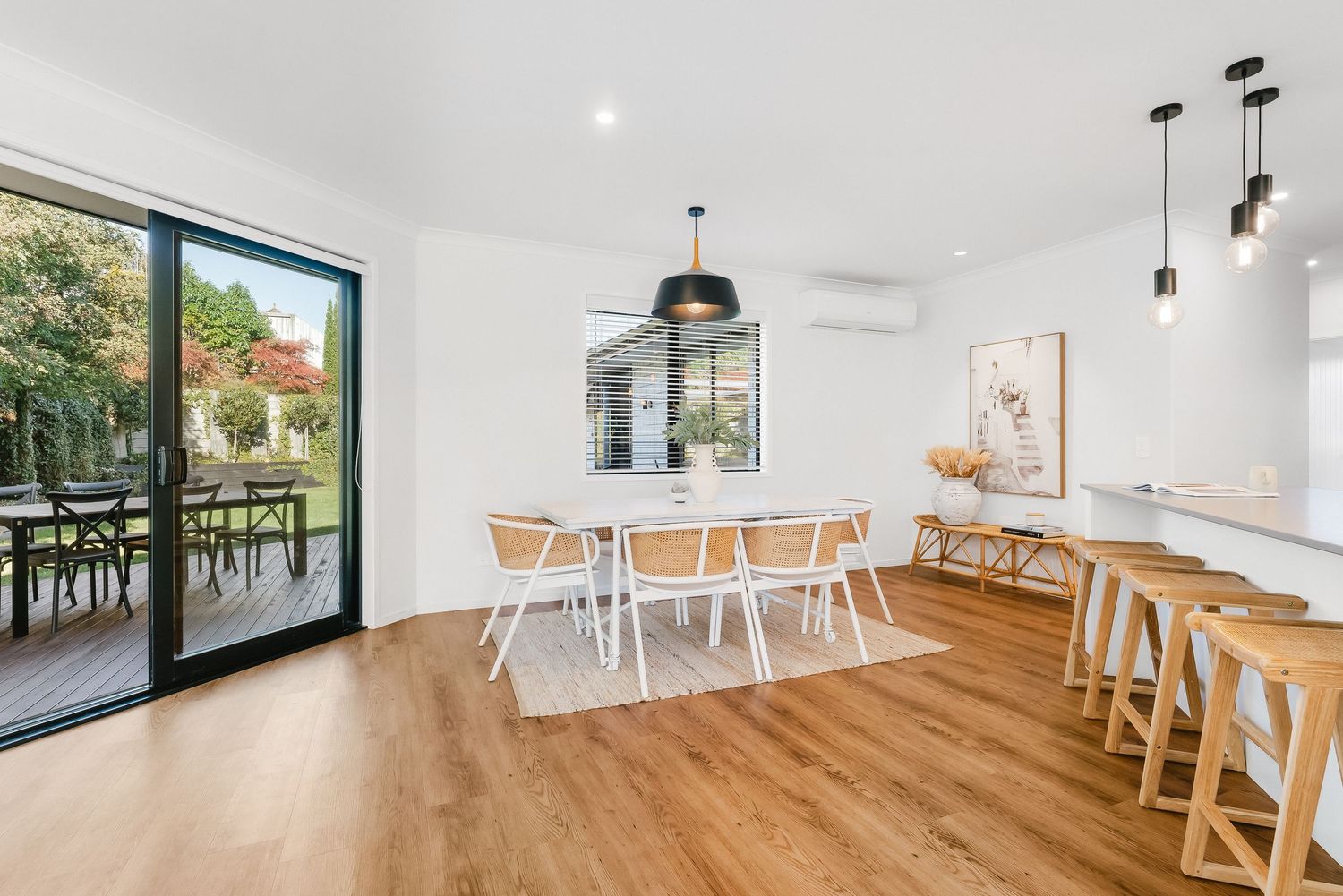 Spacious white kitchen with natural light streaming through large windows and contemporary pendant lights.