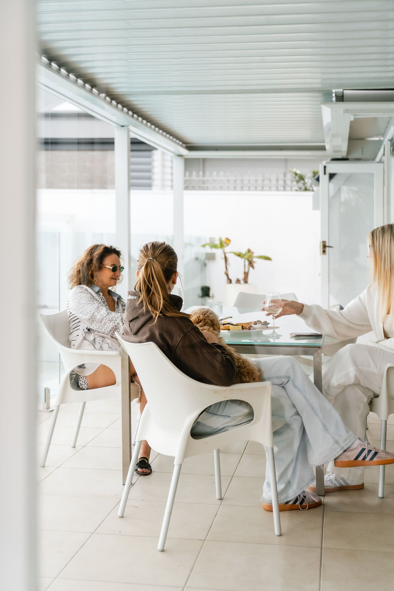 Three friends enjoying a casual dining experience in a bright white modern interior space.