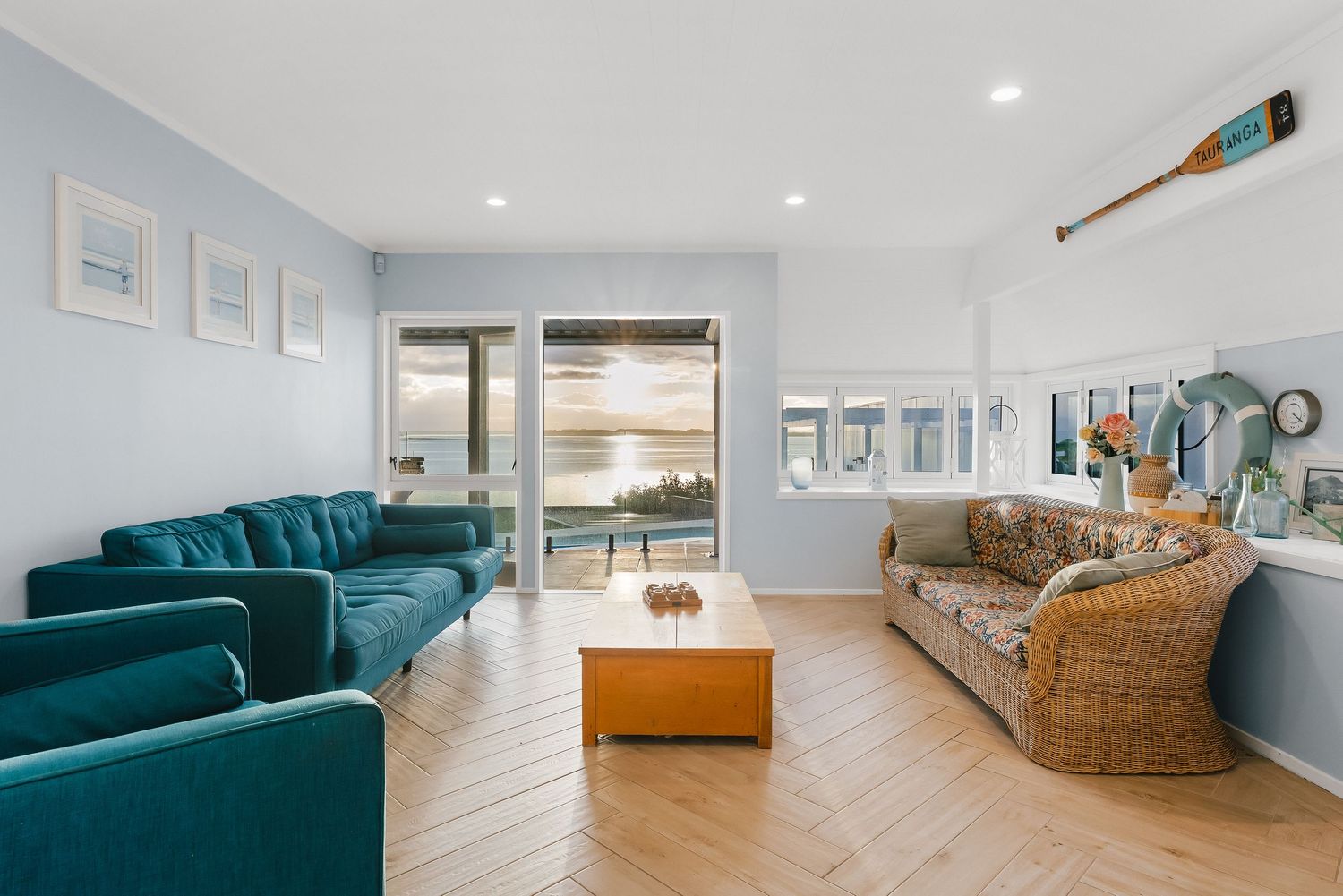 Contemporary living room featuring a teal velvet sofa and woven accent chair.