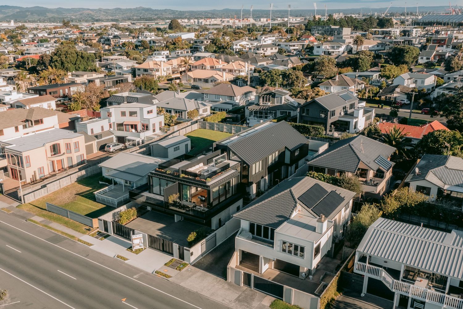 Aerial view of residential neighborhood with modern houses and streets in suburban coastal area.