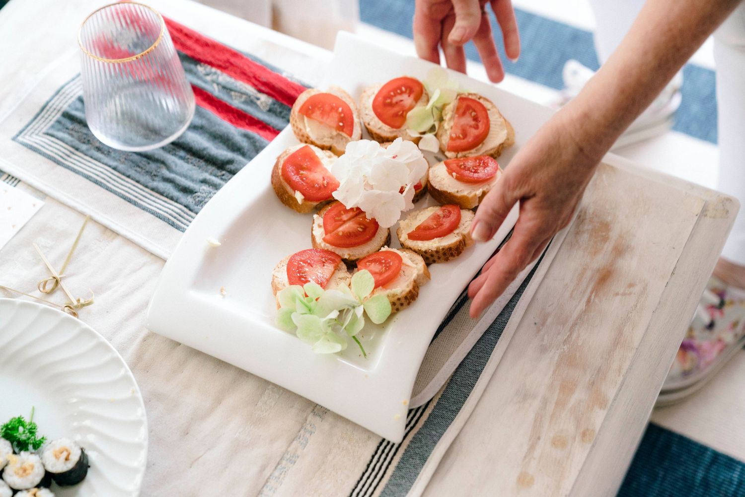 Fresh tomato and lettuce appetizers being plated on a white serving dish.