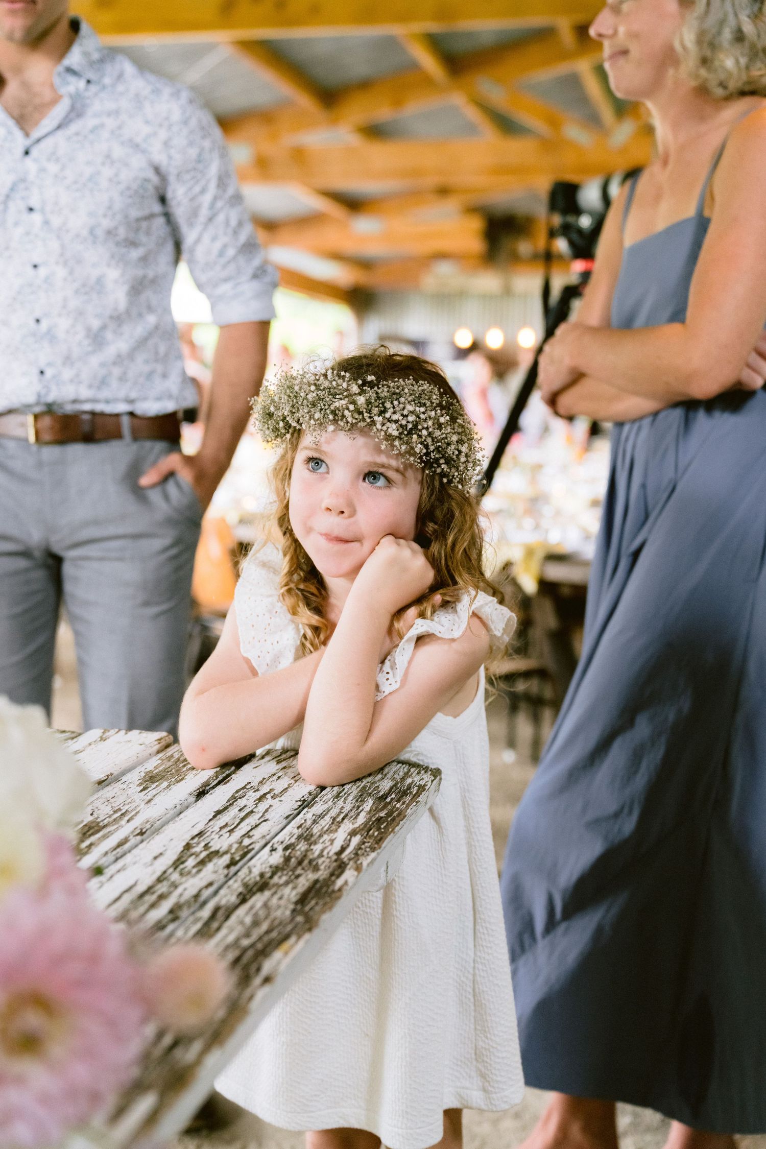 Young attendant in a floral crown and white dress at a wedding celebration.