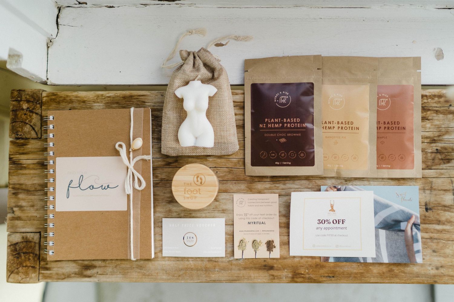 Flatlay of minimalist branding materials and packaging designs on wooden surface.