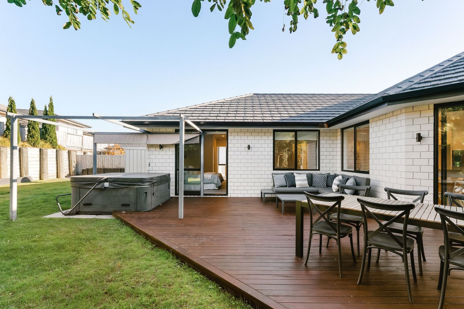 Spacious backyard deck with outdoor dining furniture and covered patio area next to a hot tub.