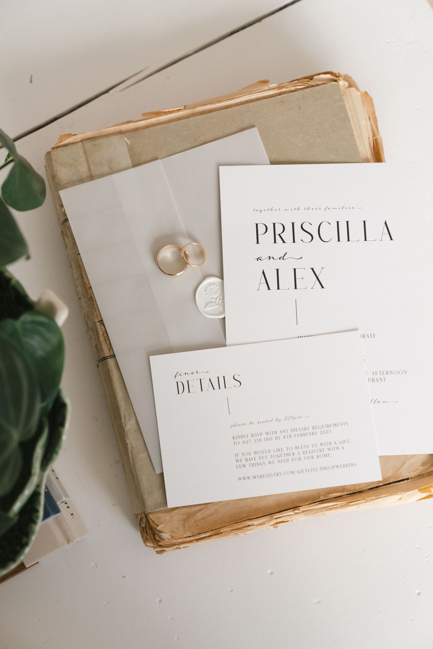 Elegant minimal wedding invitation for Priscilla and Alex with rings on white paper.