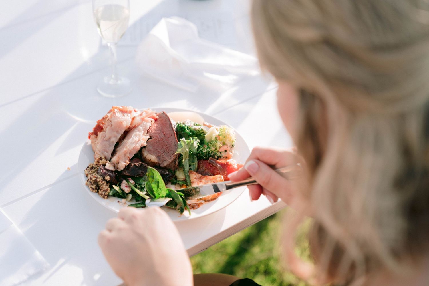 A plate of elegantly plated food with meat and greens is served at an outdoor event.
