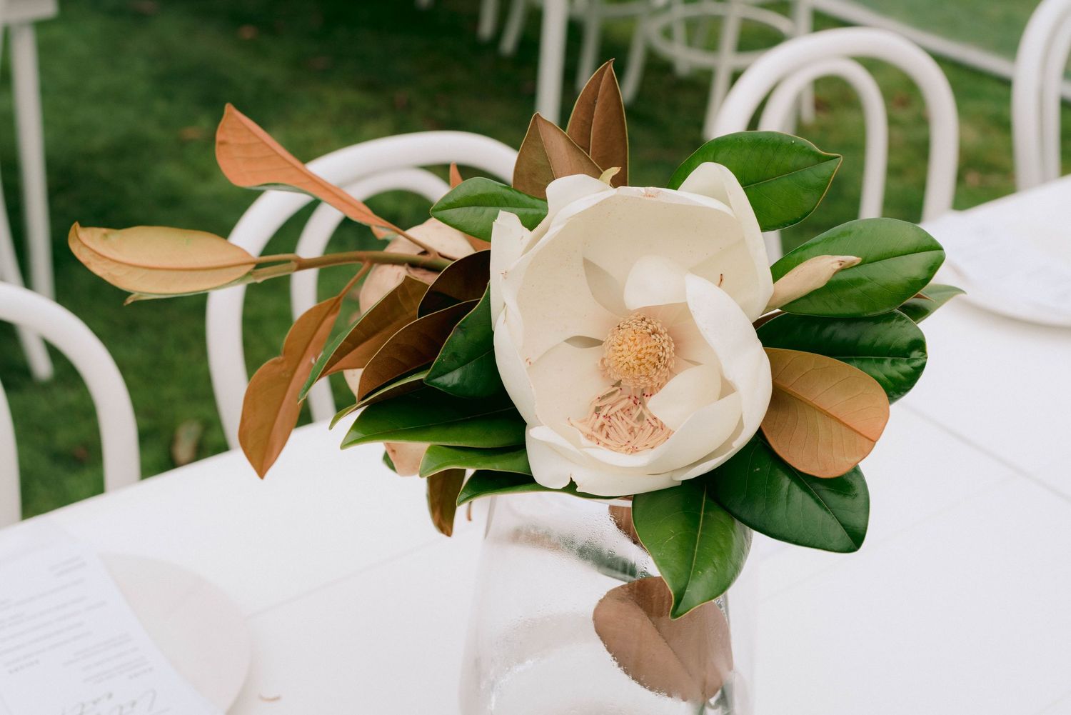 White magnolia flowers arranged on tables for an elegant wedding reception.