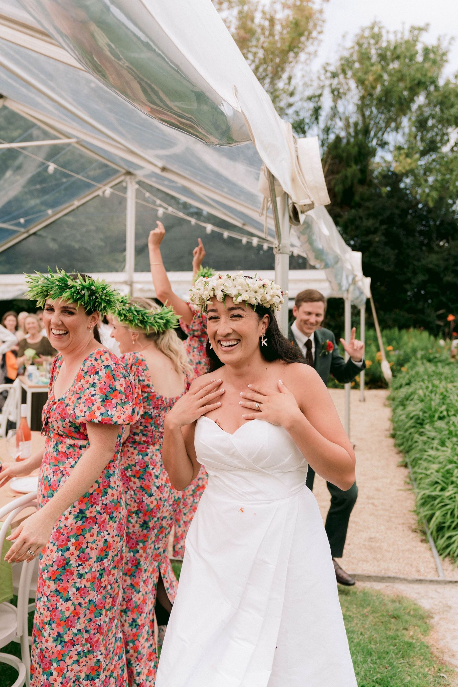 Wedding celebration under a white tent with floral decorations.
