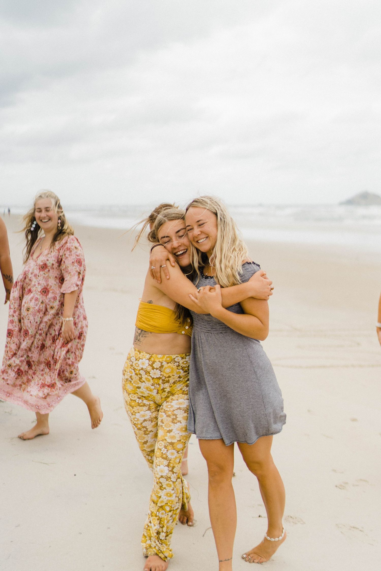 Friends sharing joyful moment together on overcast beach.