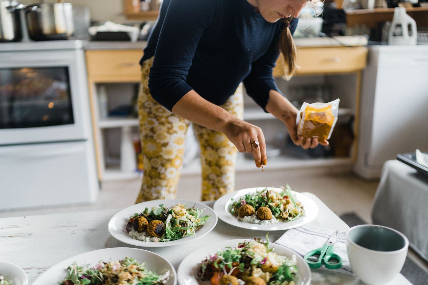 Fresh salads being plated in modern kitchen with natural lighting.