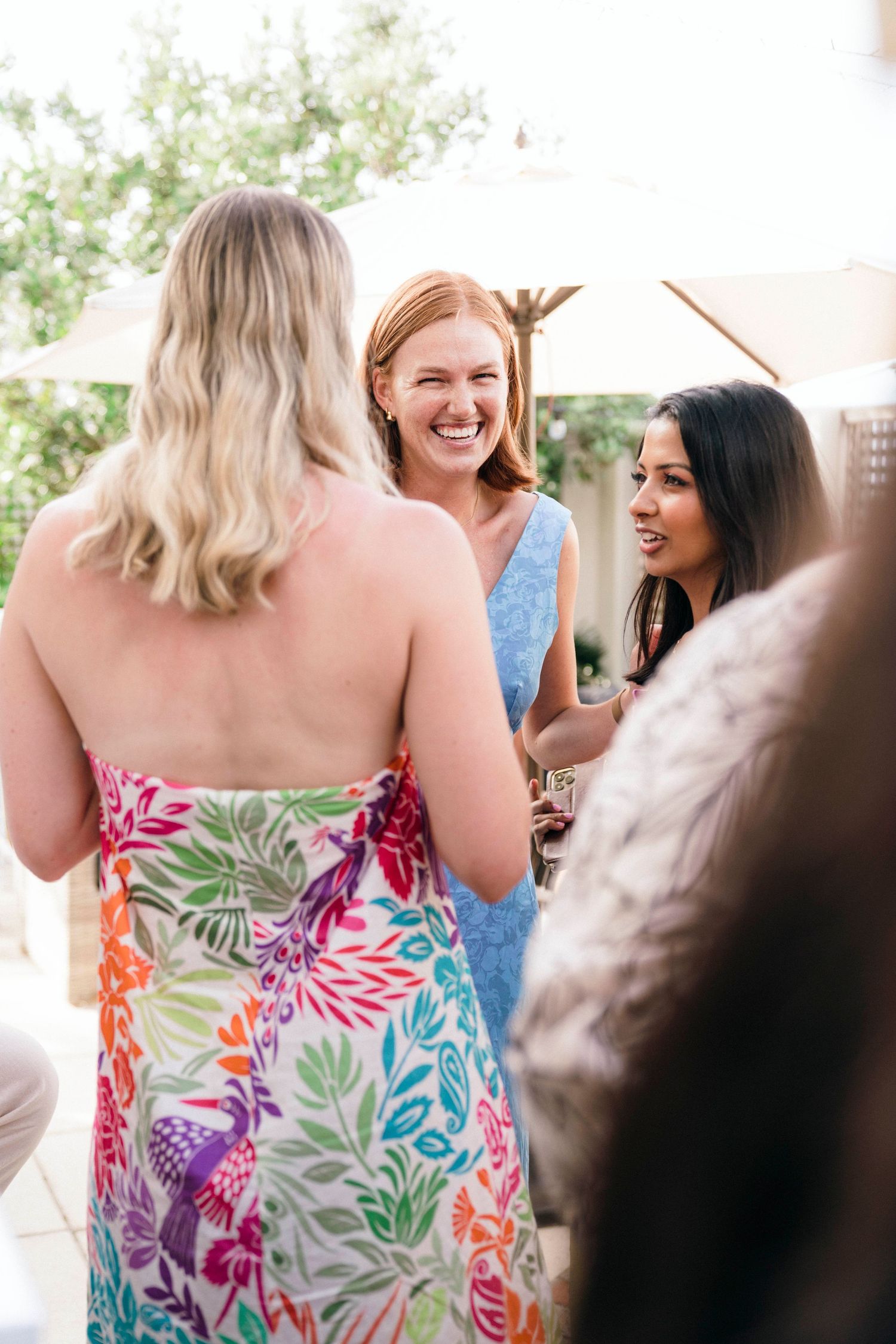 A joyful social gathering with people wearing bright floral summer dresses.