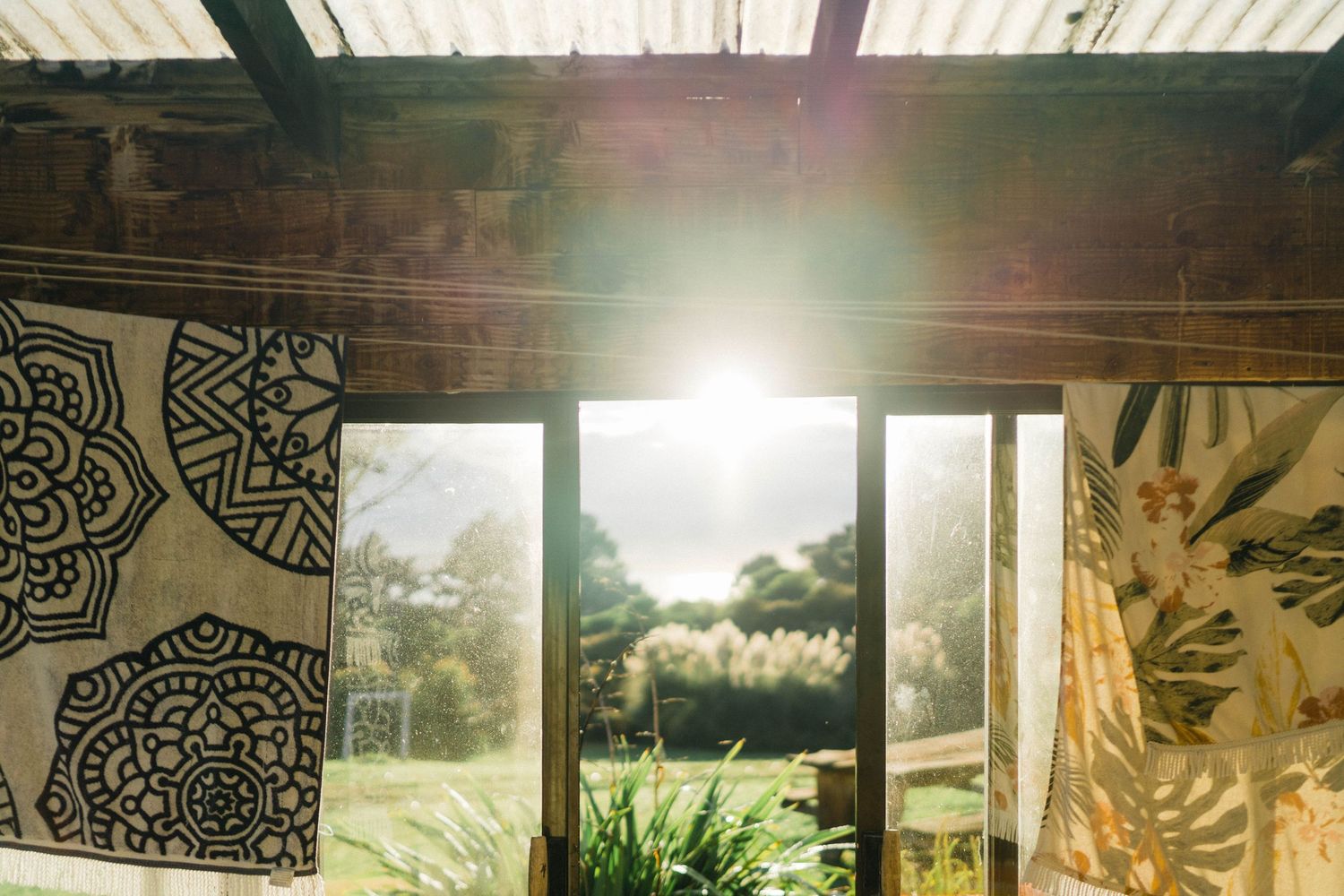 Open-air veranda with bamboo screens and tropical plants creating a natural outdoor living space on a sunny day.