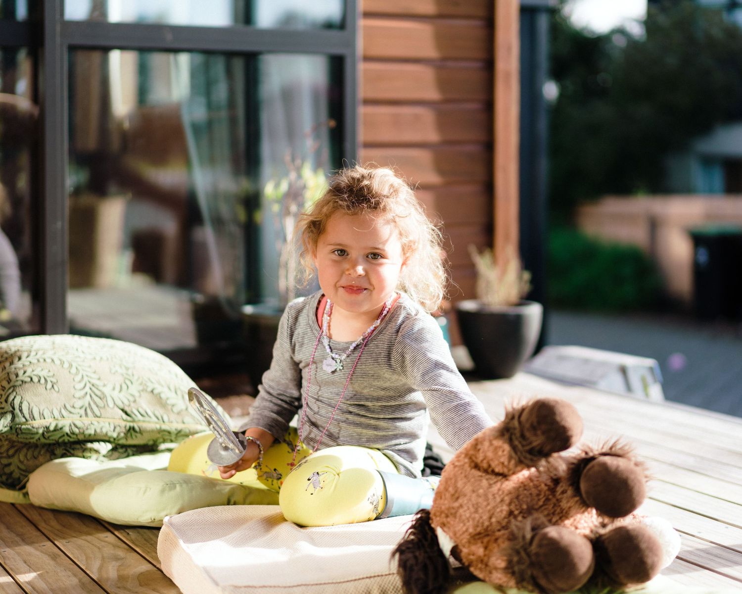 A series of four cozy indoor photos showing someone relaxing with a teddy bear on comfortable cushions and pillows.