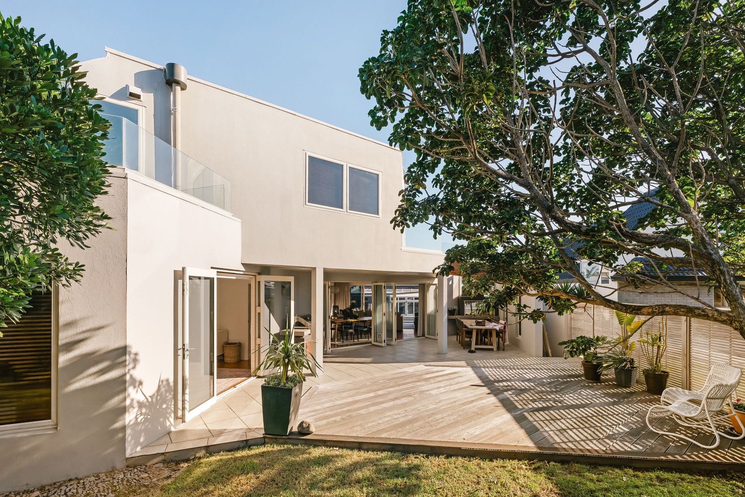 Modern white coastal home exterior features expansive decks and large windows with stunning ocean views.