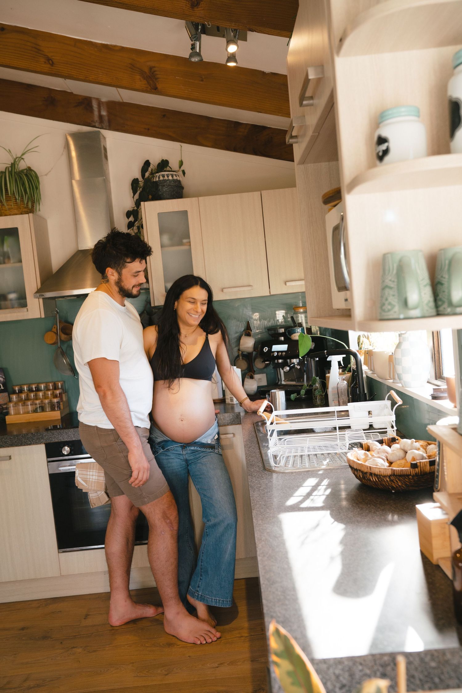 People spending time together in a modern kitchen with wooden beams and white cabinets preparing food and drinks.