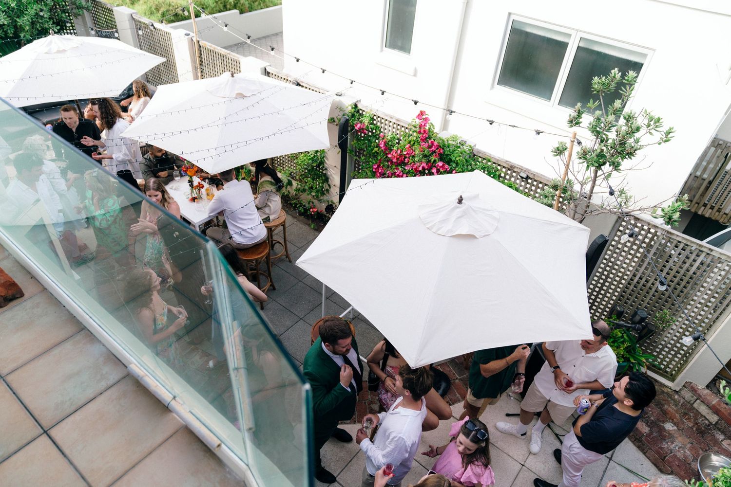 Guests gather under white umbrellas on an outdoor patio during a celebration party.
