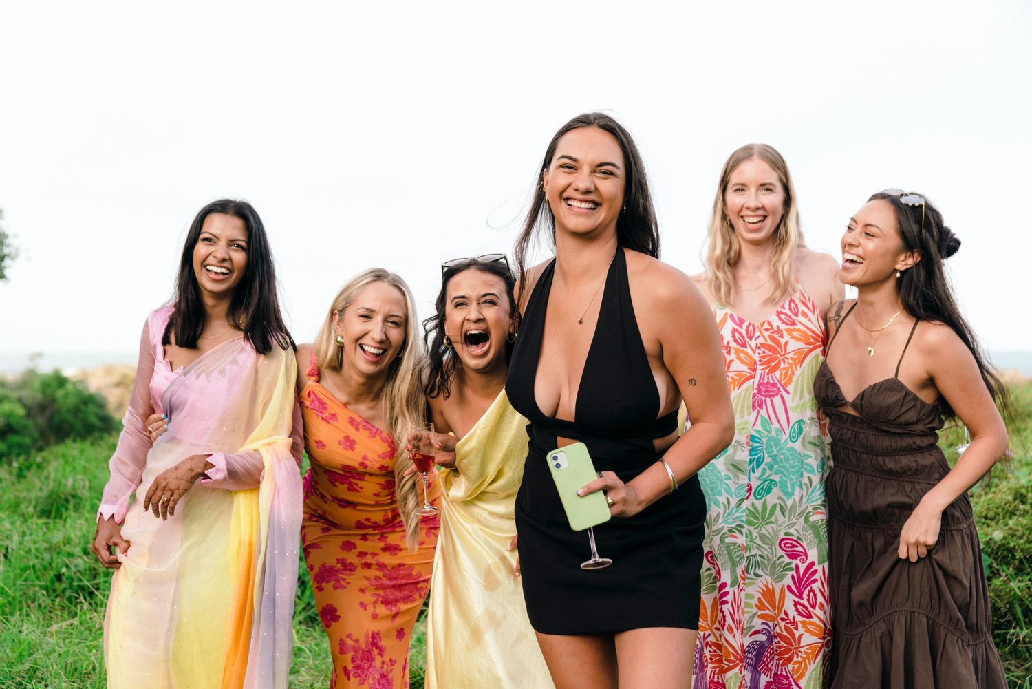 Group posing together in colorful summer dresses against a natural backdrop.