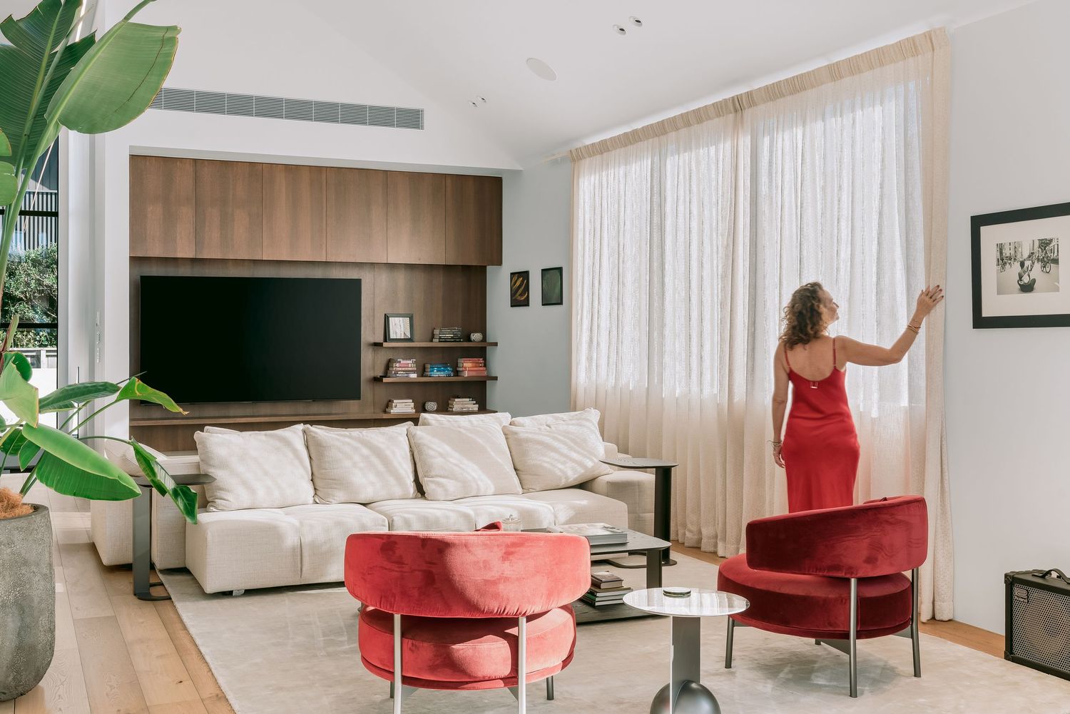 Modern luxury apartment interior with minimalist furniture, red accent chairs and large windows for natural light.