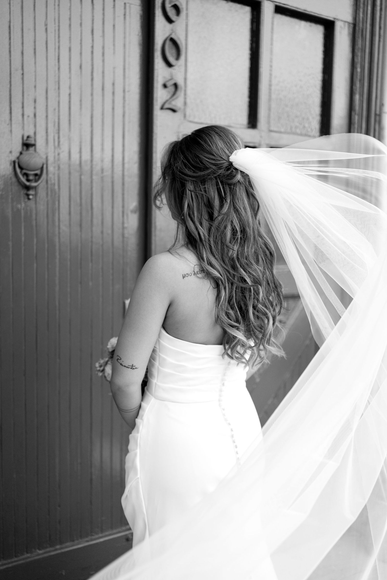 Back view of a bride with flowing veil and curled hair approaching door number 602.
