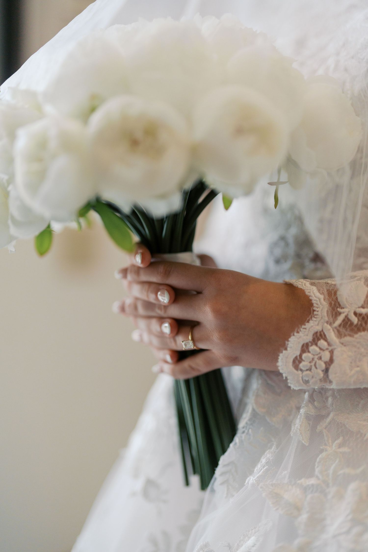 Close up of lace-covered hands holding an elegant white bouquet.