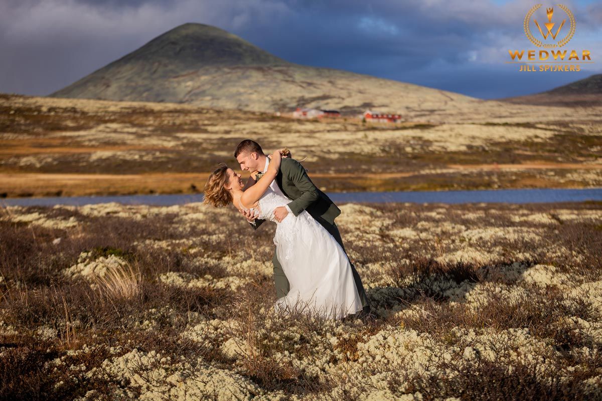 Dramatic wedding dip pose against rugged mountain landscape.