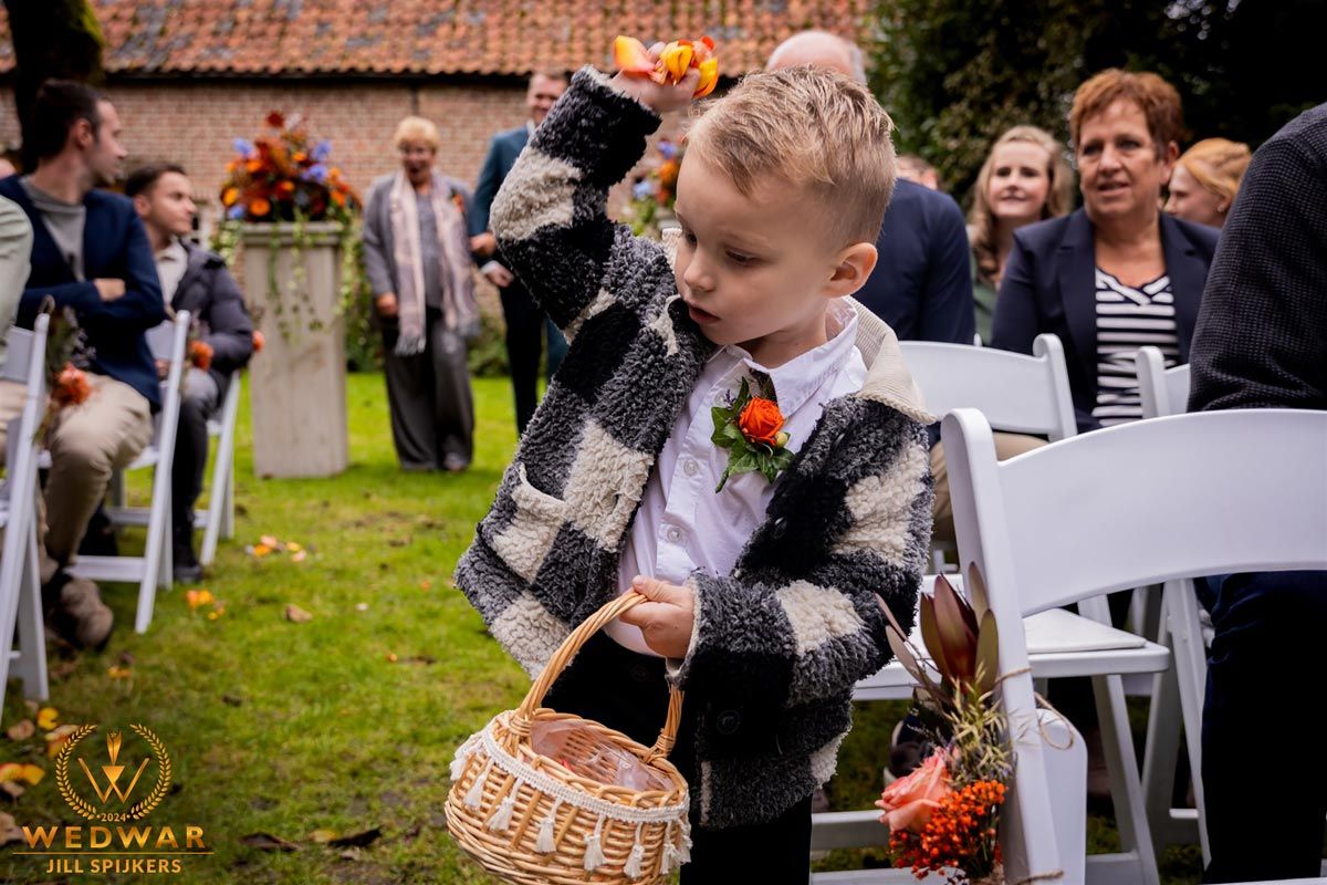 A small ring bearer in plaid carrying baskets down the wedding aisle.
