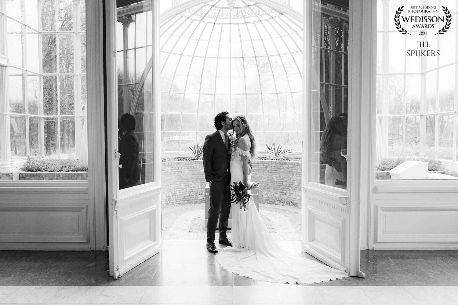 Elegant black and white wedding photo in conservatory with domed glass ceiling.