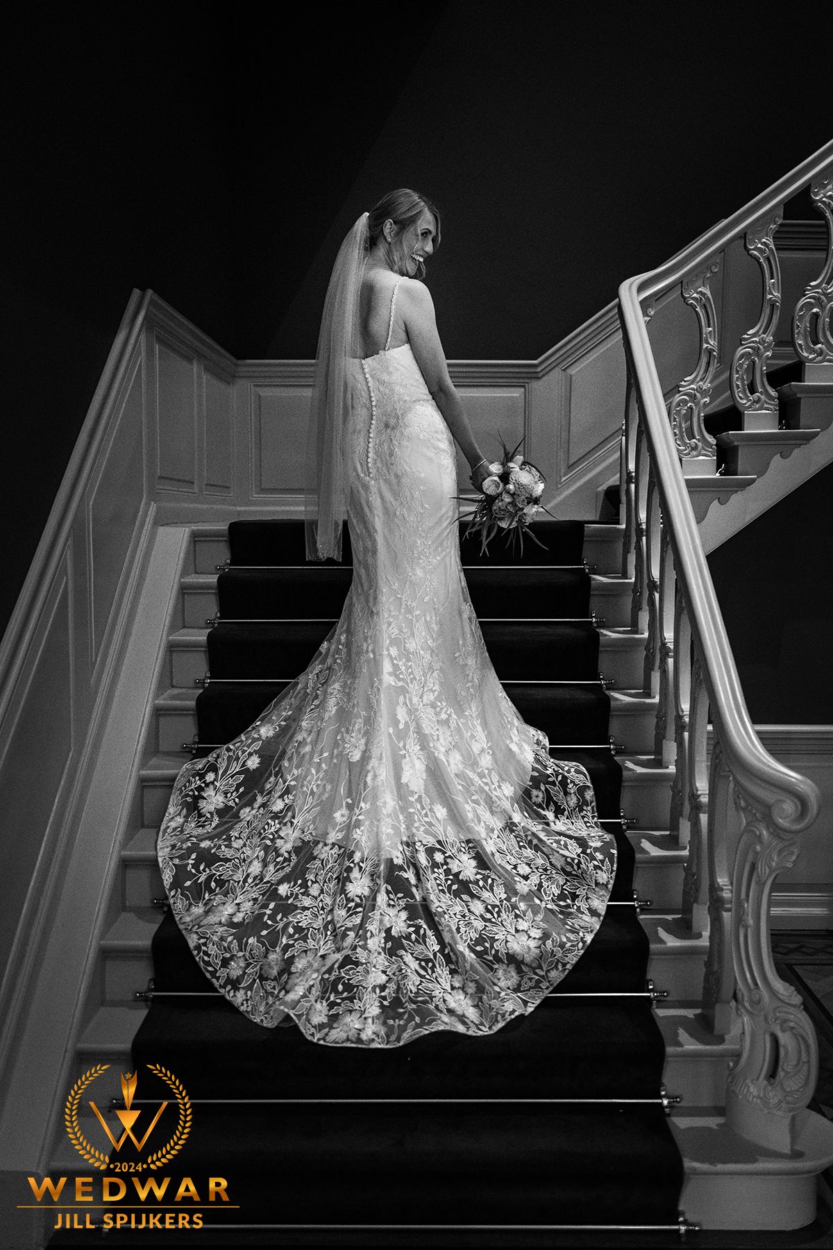 Elegant lace wedding dress with cathedral train photographed on grand staircase.