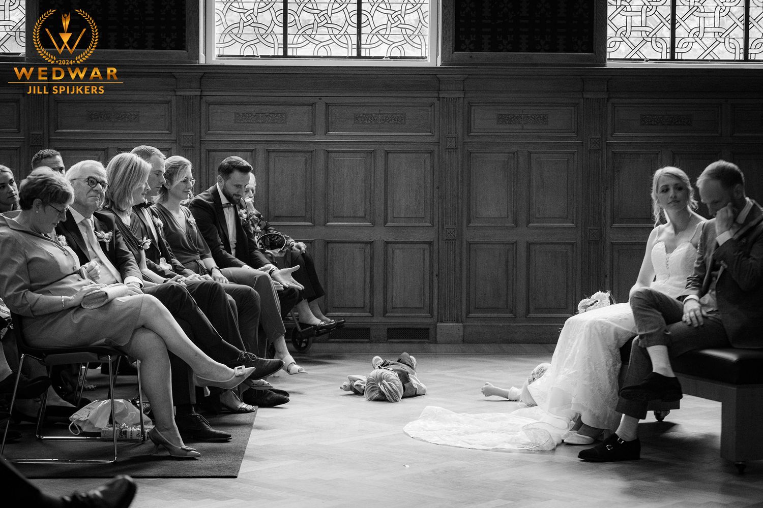 Black and white wedding ceremony with guests seated in historic wooden interior.
